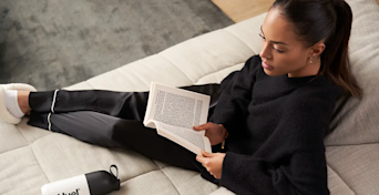 person sat on a sofa reading a book with their feet up