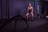 Woman using ropes for conditioning training at a gym