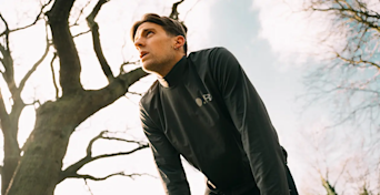 man bent over with his hands on his knees while outside catching his breath