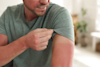 man lifting his tshirt sleeve to show his sunburn tan line