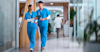doctors walking down a hallway holding a clipboard and smiling