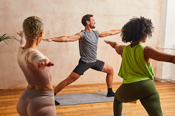 Three people doing yoga poses on yoga mats