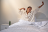 woman waking up in bed and stretching with her eyes closed
