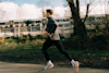 man running along a road outside next to a trainline with a train in the background