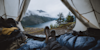 beautiful nature scenic view through the opening of a tent with a persons feet in the foreground