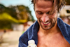 man outside who is wet and has a towel on his shoulders holding a huel ready-to-drink