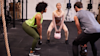 three people at the gym doing kettlebell squats