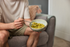 man sat on a sofa eating huel hot and savoury from a bowl