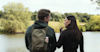 man and woman standing in front of a lake looking at one another the man has a backpack on with a Huel Lite in the pocket
