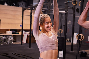 woman at the gym stretching and smiling