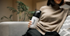 woman on a sofa holding a Huel shaker