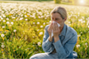 woman sat in a field blowing her nose