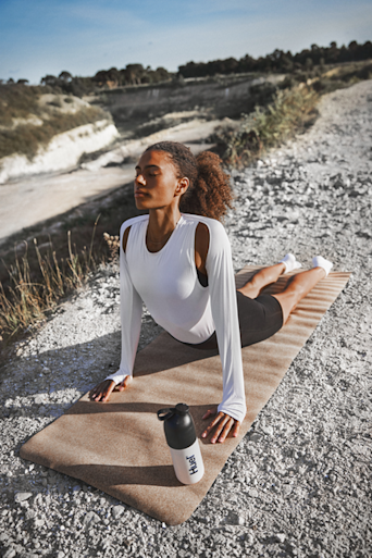 woman stretching on a mat outside in the sun