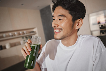 man drinking Huel Daily Greens from a Huel Bottle while smiling