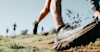 close up of a trail runners running shoe in action running over mud