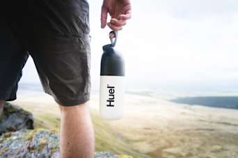 Man holding a shaker while hiking on top of a mountain