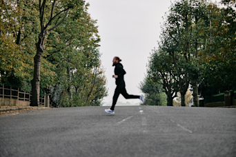 russ cook running across a road with trees either side
