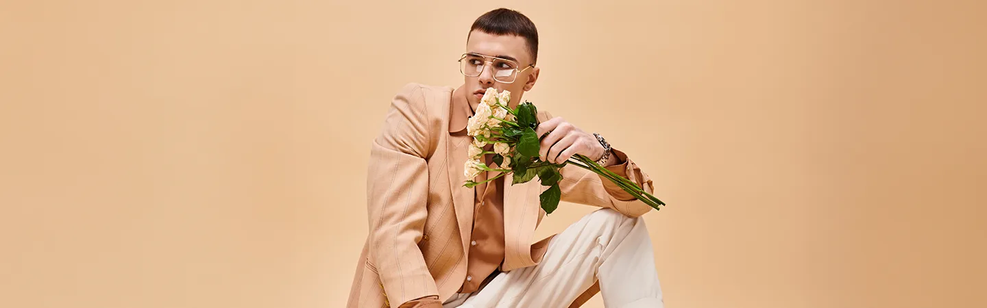 Istuva silmälasipäinen henkilö kädessään kukkia