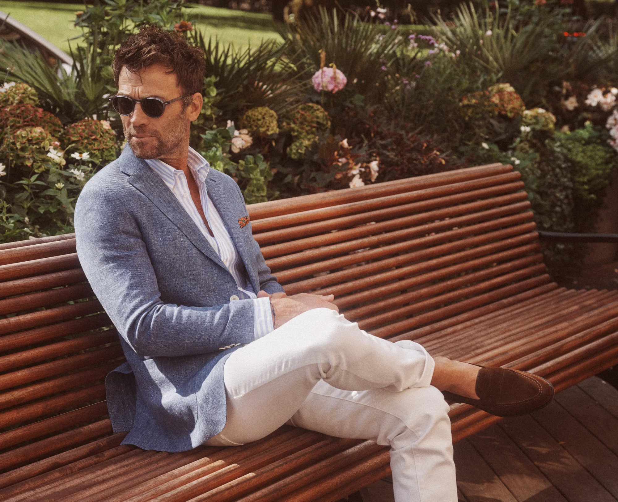 Turo-pukuun pukeutunut mies istuu puiston penkillä aurinkolasit päässä.