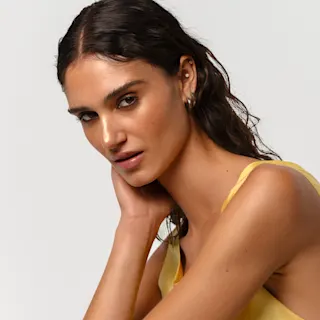 Tummahiuksinen nainen nojaa kevyesti käteensä.