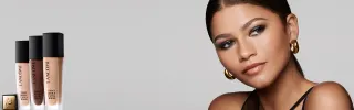 Näyttelijä Zendaya katsoo sivulle ja hänen vieressään on Lancômen Teint Idole meikkivoidetuotteita.