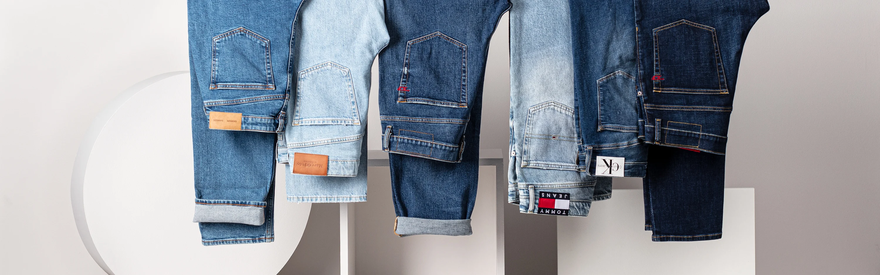 Huippumerkkien, muun muassa Calvin Kleinin ja Tommy Hilfigerin, farkkuja erilaisilla väreillä ja kulutuspinnoilla ripustettuna vaatetangolle.