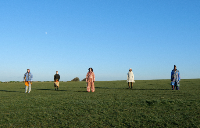 Models stood in a field with blue skies wearing sustainable fashion