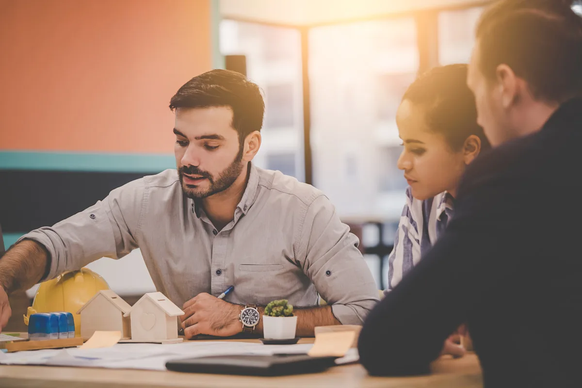 Three people sitting around a table and reviewing documents.