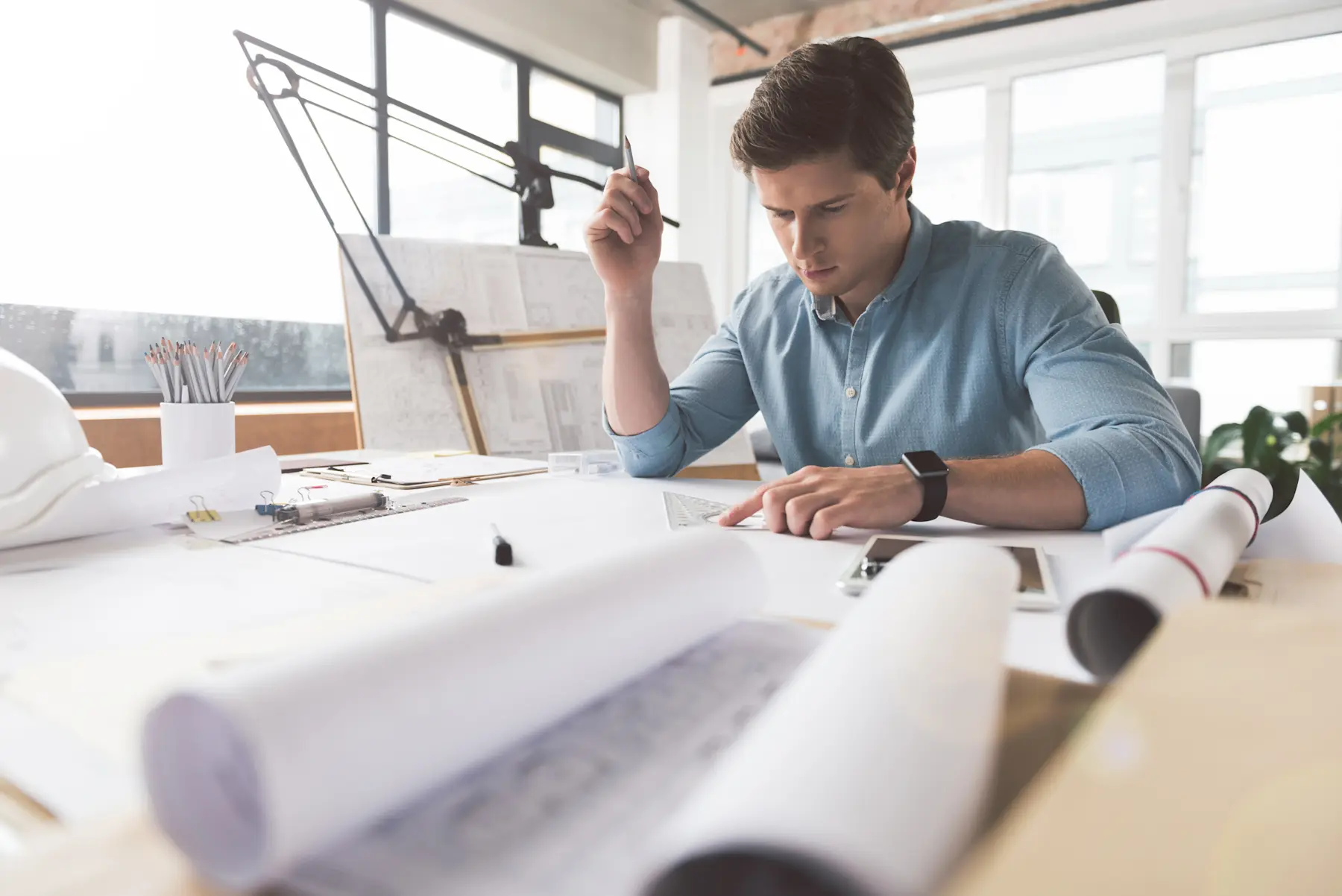 Architect reviewing blueprints on drafting table