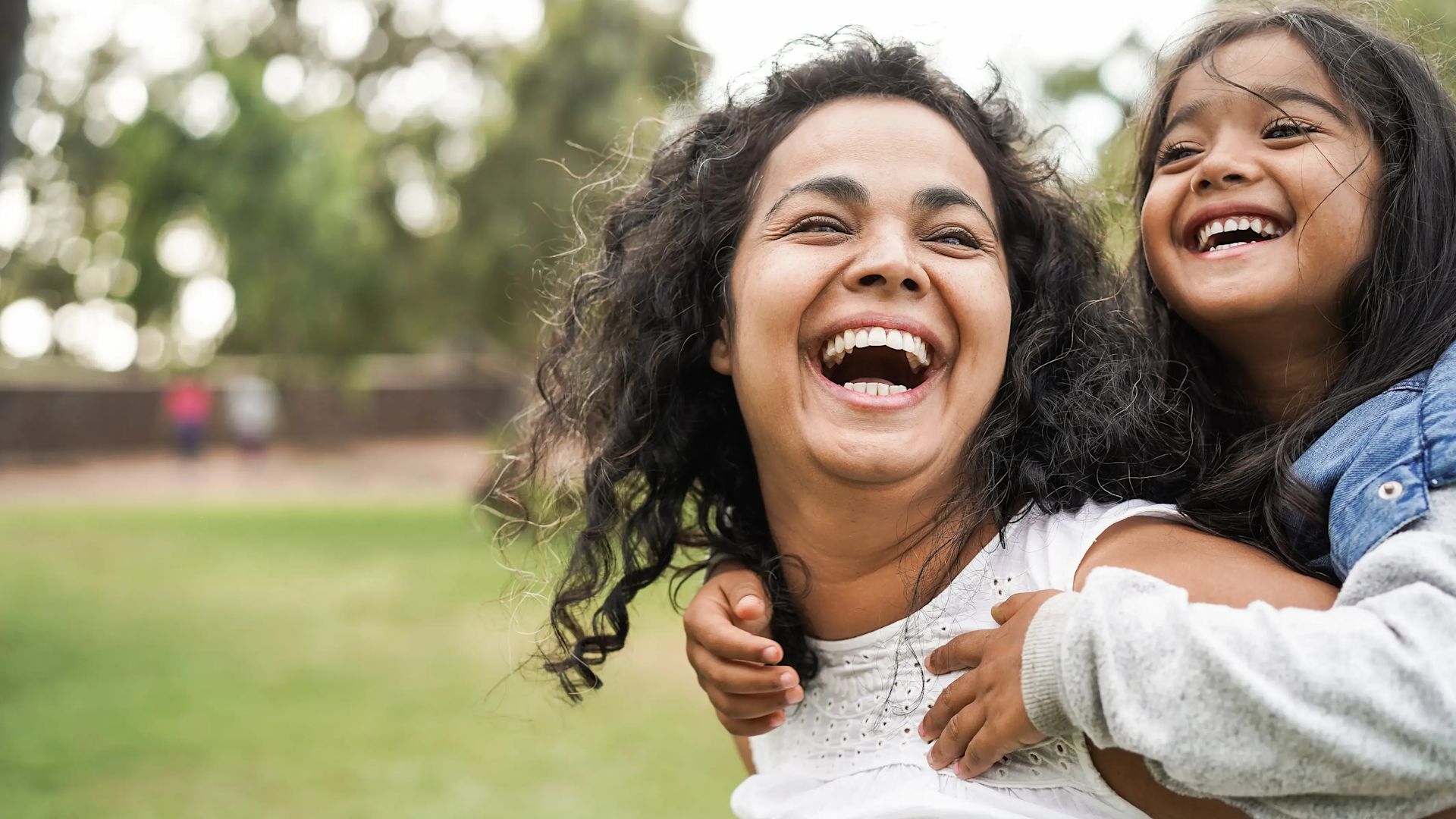 Un enfant sur le dos d’une femme, tous deux sourient.