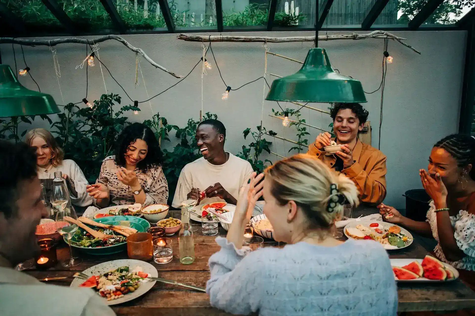 A group of friends sitting at a table, happily eating and engaging in lively discussion over a meal