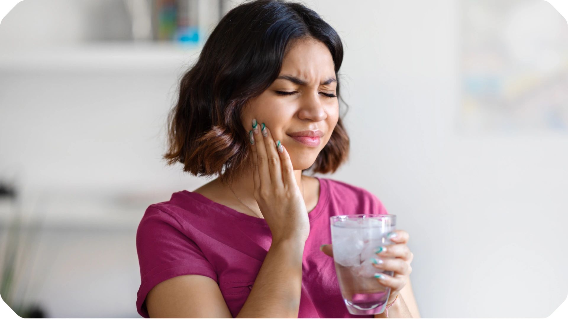 A woman places her hand on her cheek, showing a moment of pain in her teeth