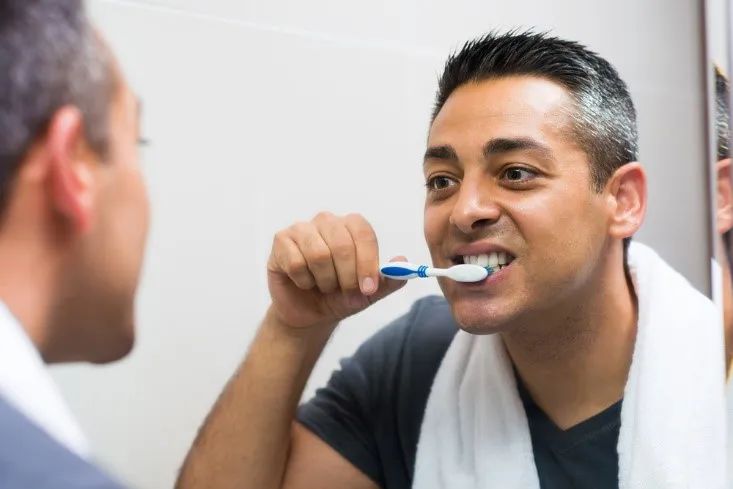 A mirror reflection of a man brushing your teeth - Be Sure to Gently Scrub Your Teeth