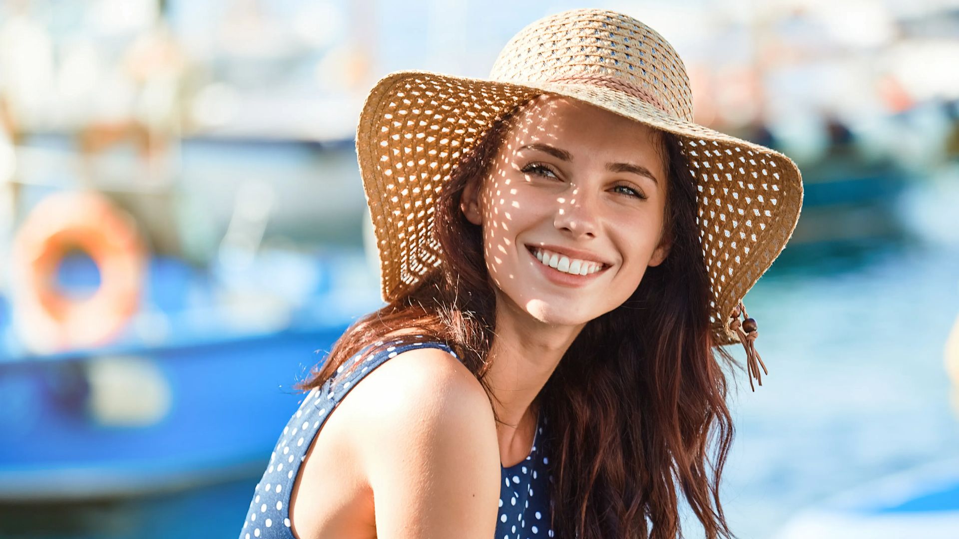 Une femme souriante avec un chapeau sur la tête.