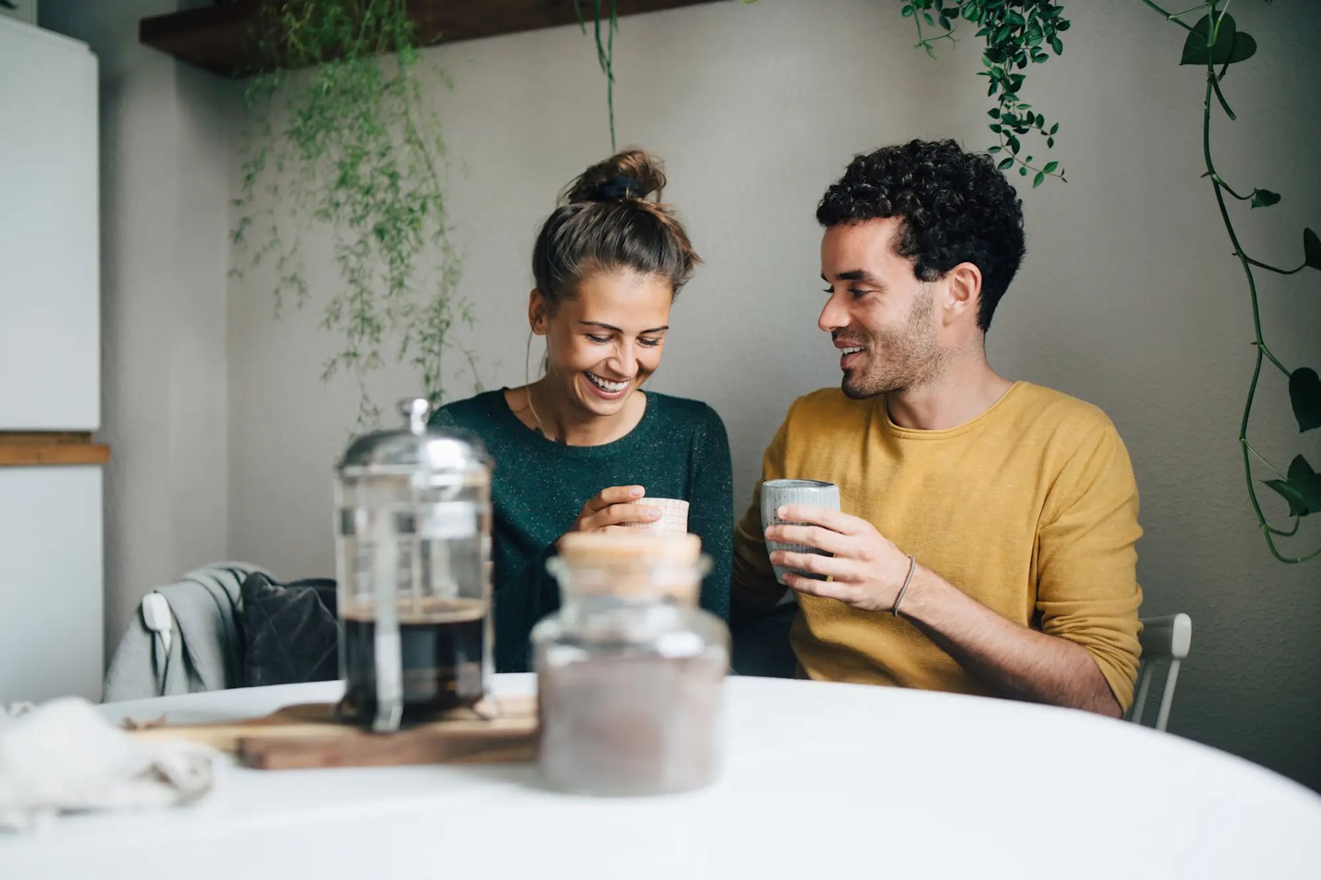 A man and woman sit at a table, enjoying coffee together in a cozy setting