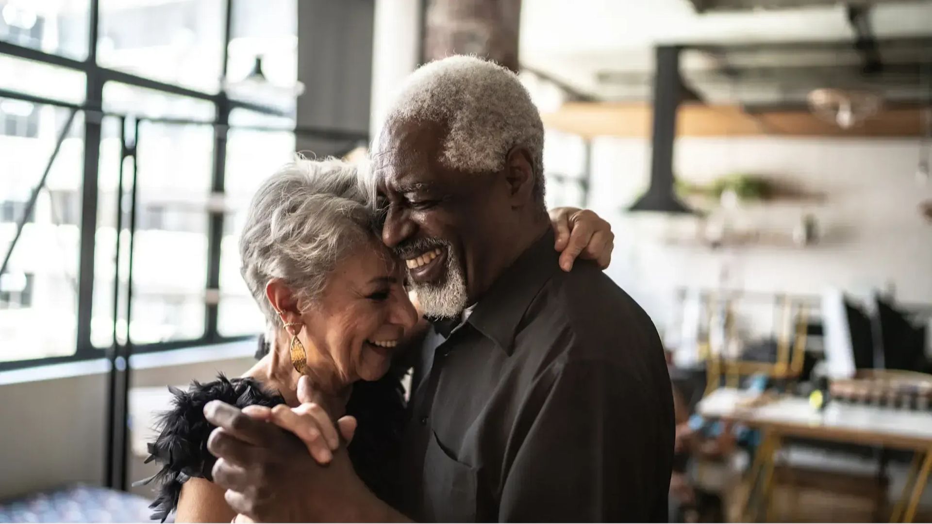 An elderly couple sharing a dance in home, radiating happiness in a charming and intimate setting