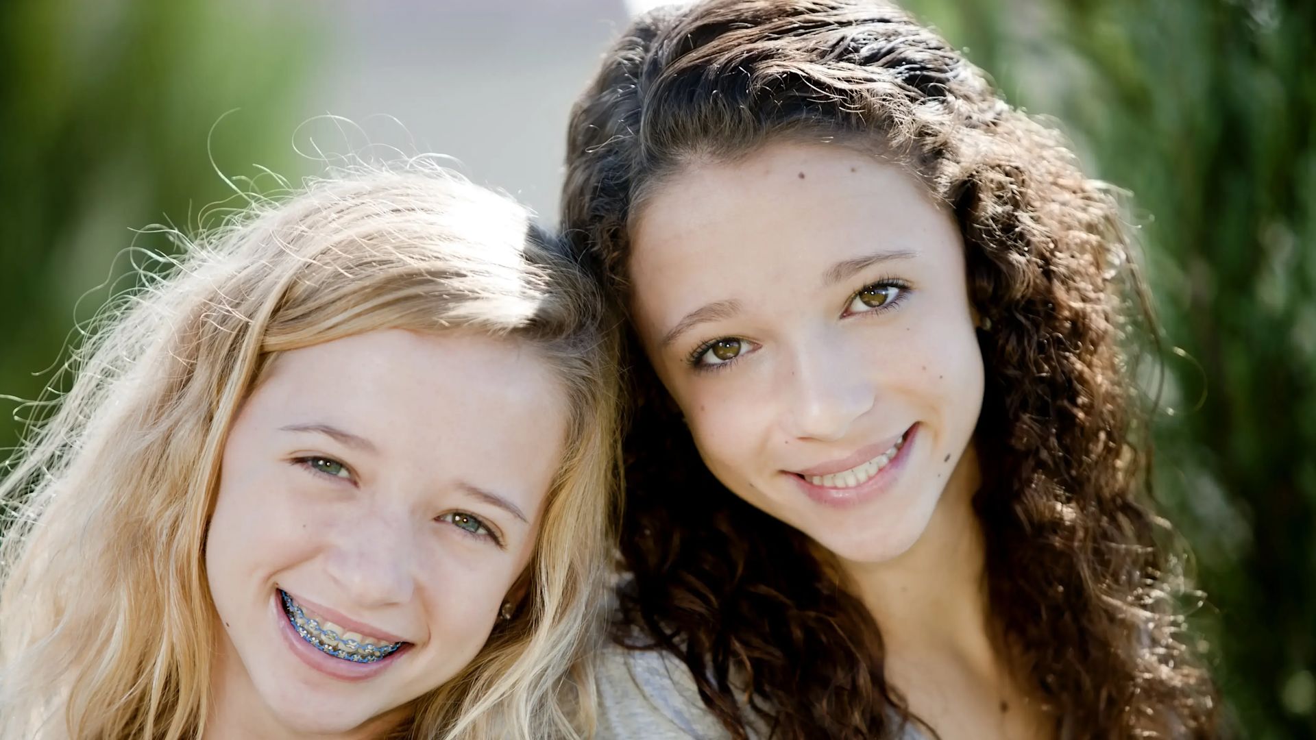 Deux filles avec des appareils dentaires souriant à la caméra.