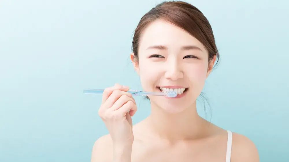 Une jeune femme asiatique se brossant les dents.