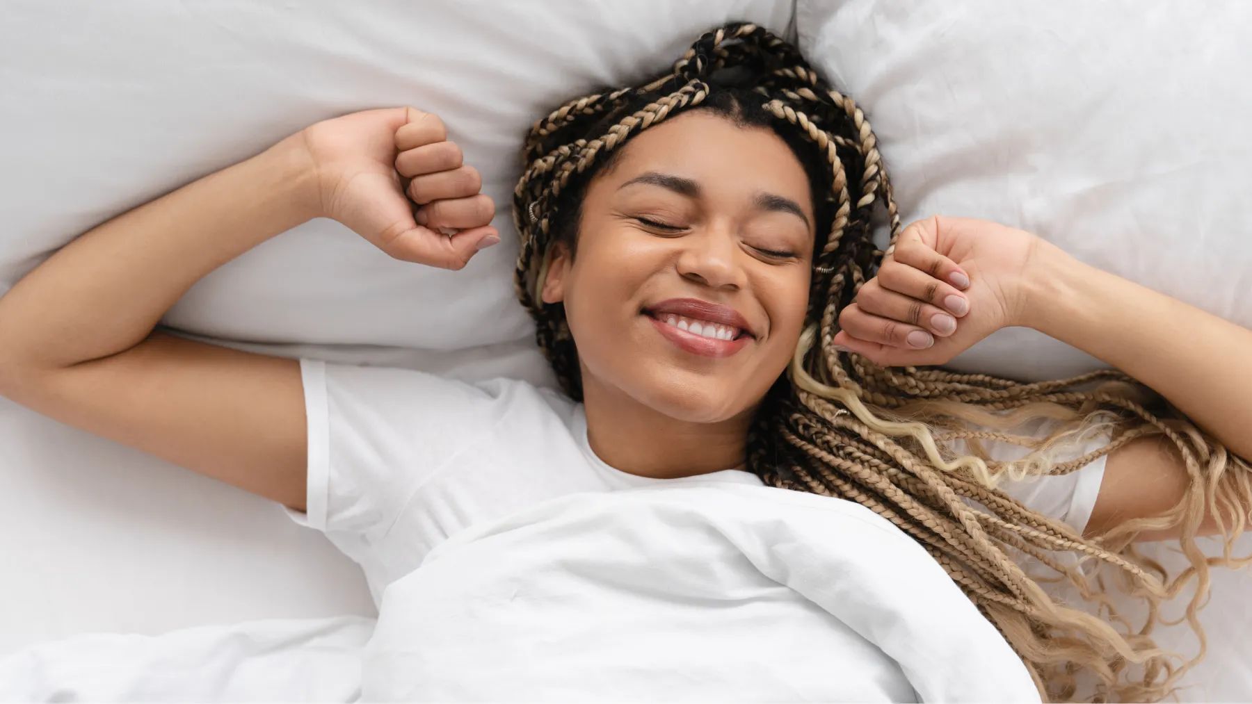Image of a smiling woman in bed right after waking up, hero for Causes of morning breath article