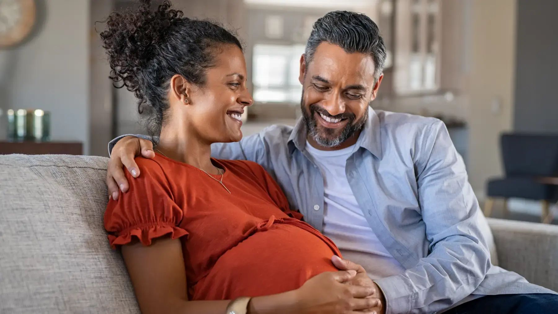 A couple, with the woman visibly pregnant, showcasing their excitement for the upcoming arrival