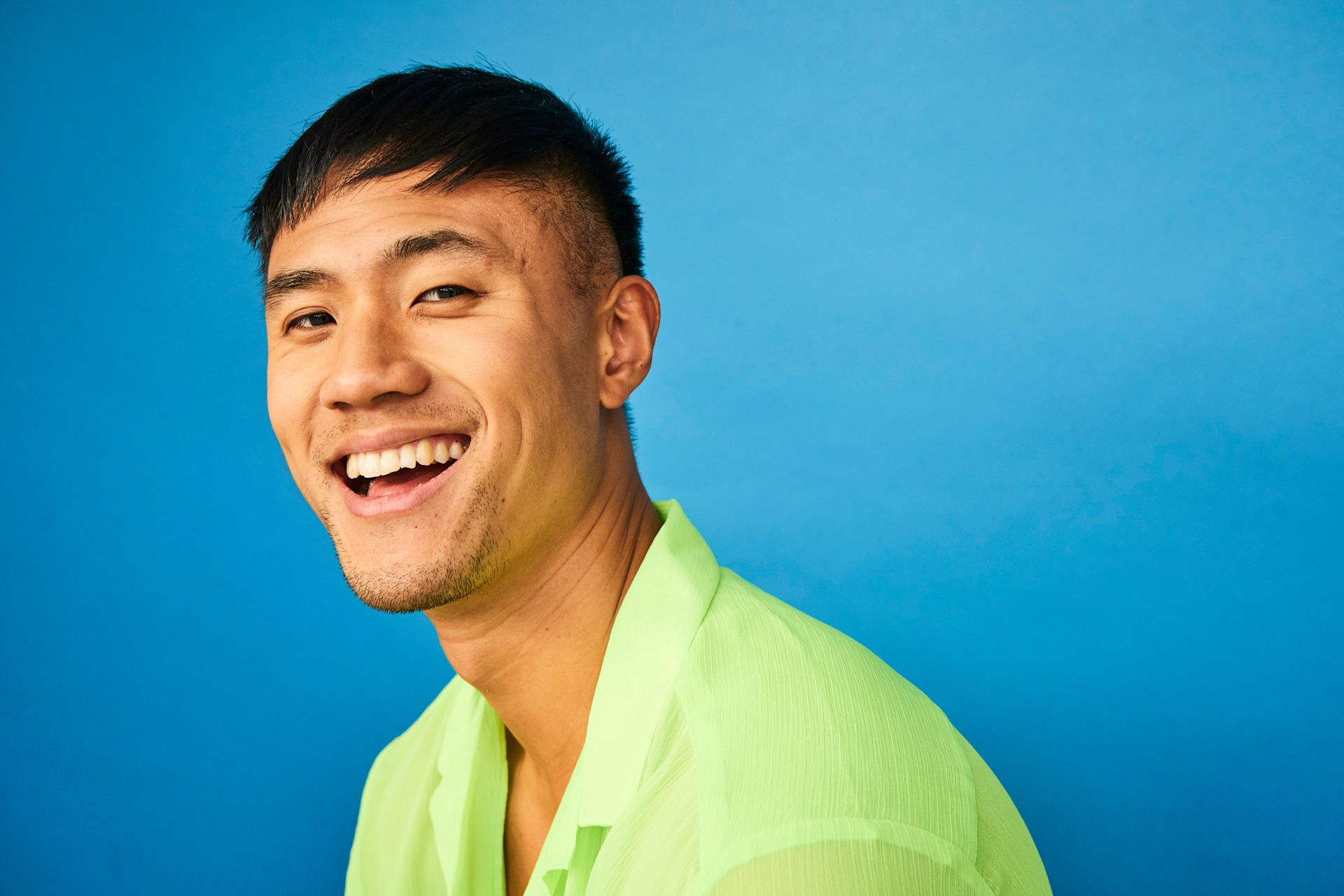 Jeune homme souriant portant une chemise verte