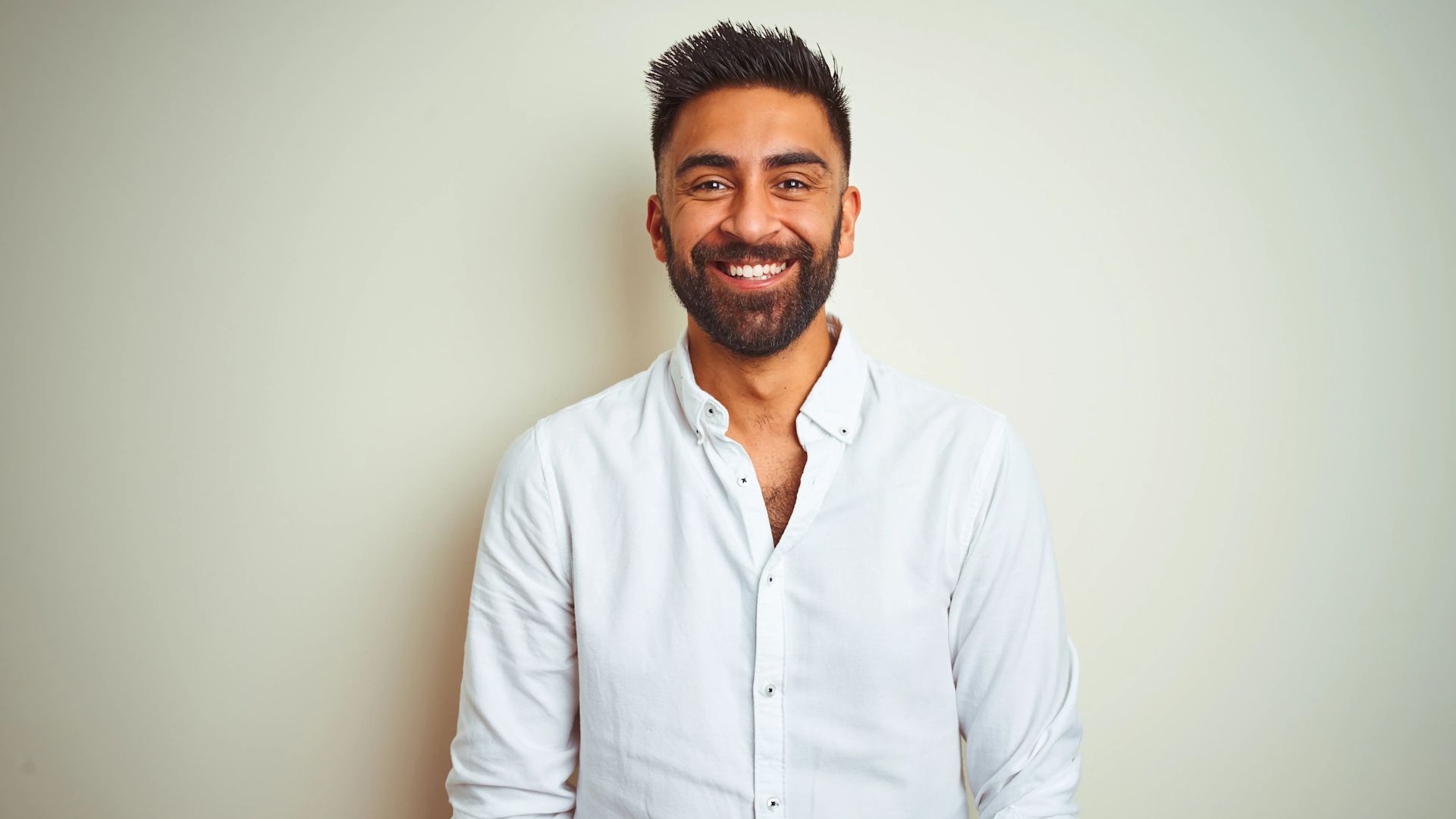 Un homme souriant portant une chemise blanche