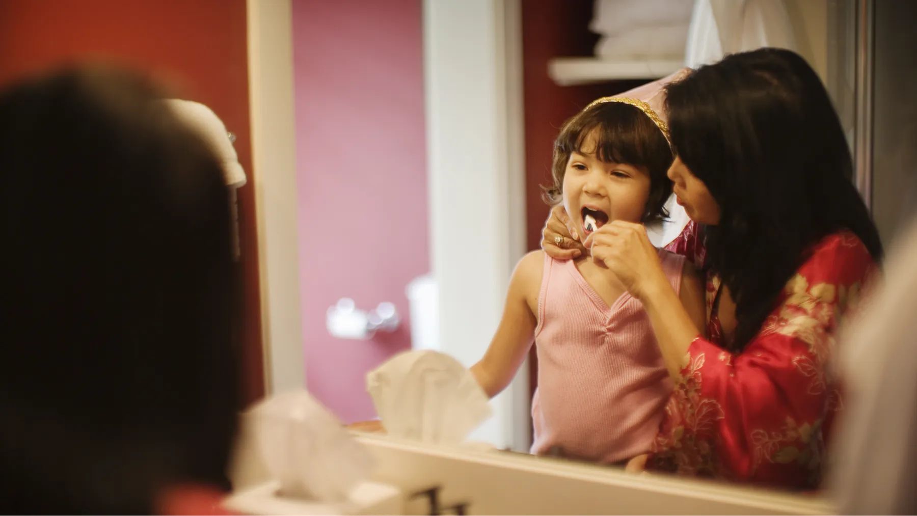 A mother helps her kid brush their teeth properly, they smiles with joy caring for kids teeth