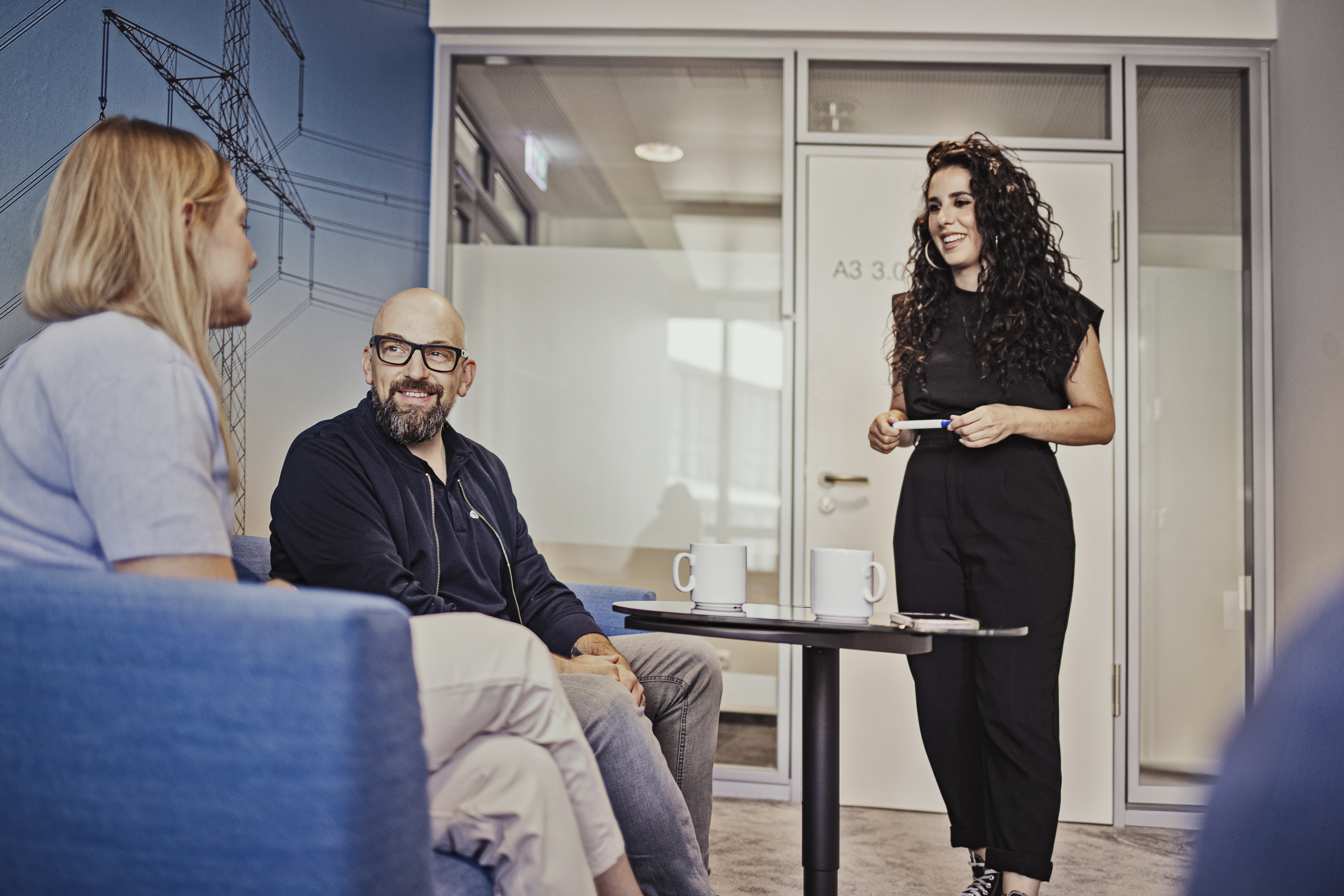 Zwei Frauen und ein Mann unterhalten sich im Meetingraum