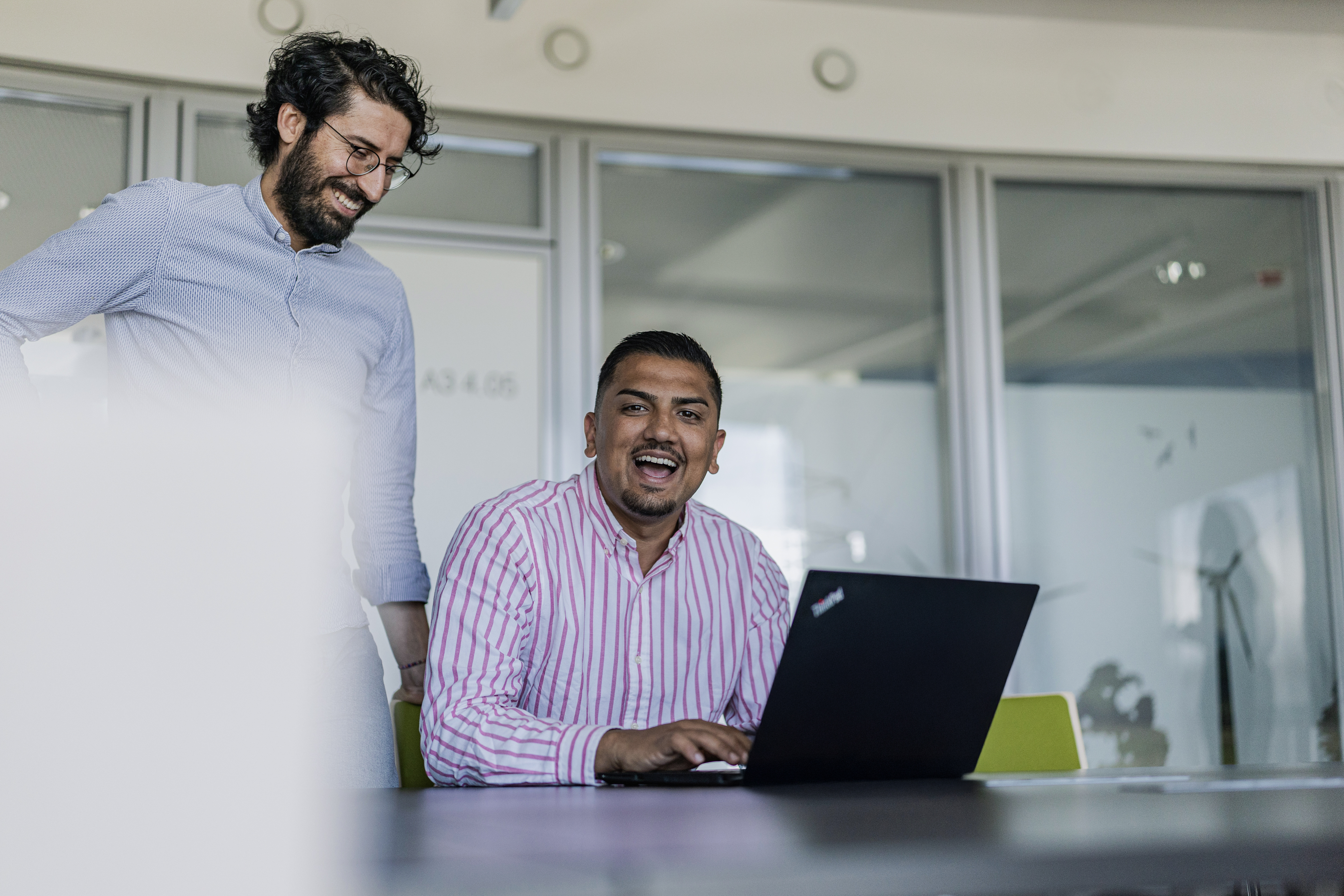 Zwei Männer im Meetingraum lachen