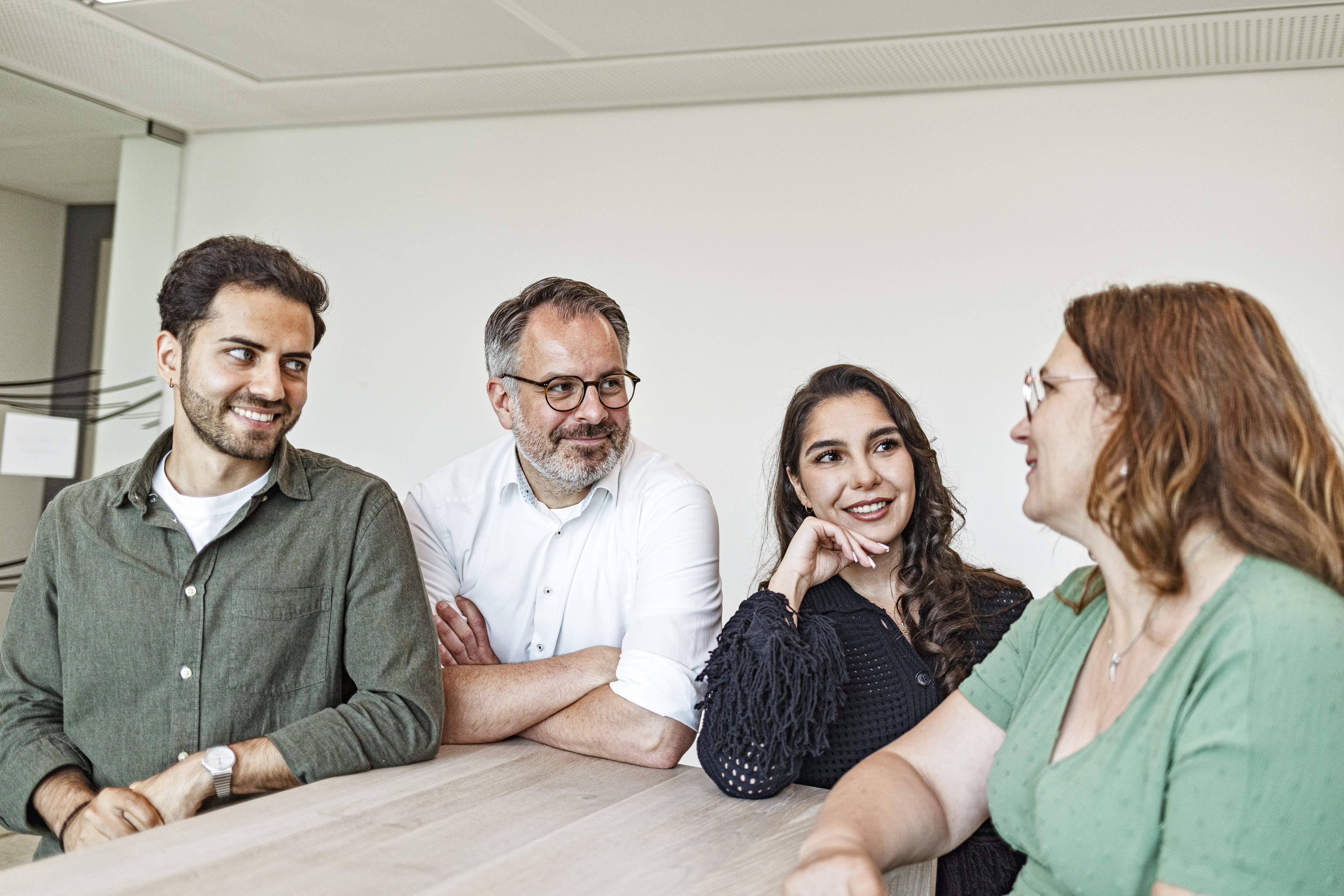 Zwei Männer und zwei Frauen unterhalten sich in der Kaffeeküche