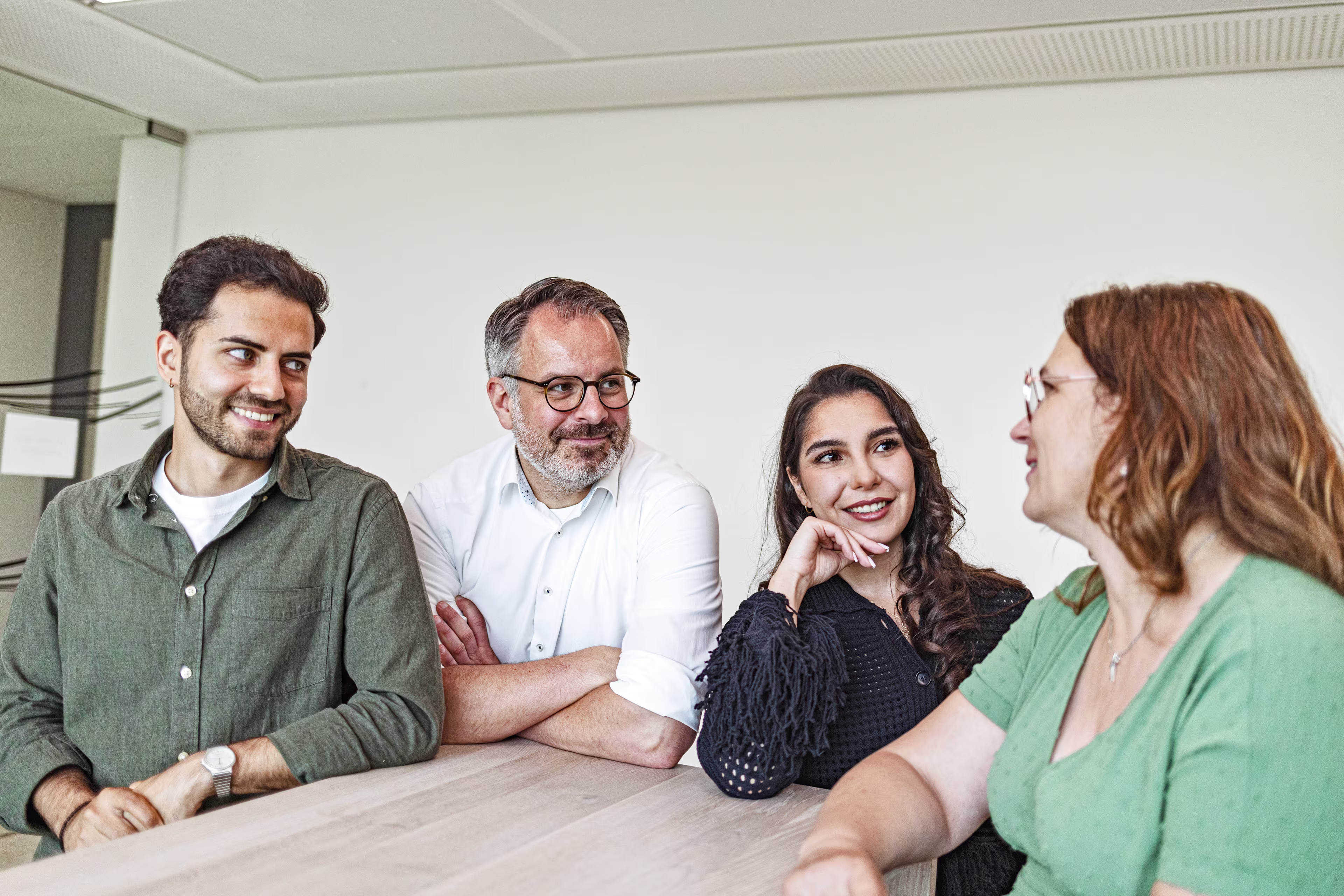 Zwei Männer und zwei Frauen unterhalten sich in der Kaffeeküche