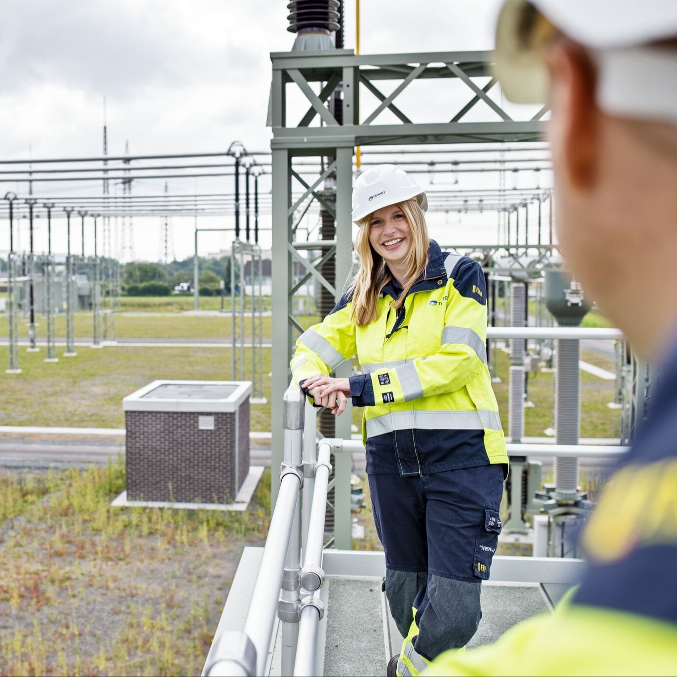 Frau mit Helm und Sicherheitskleidung bei Umspannwerk