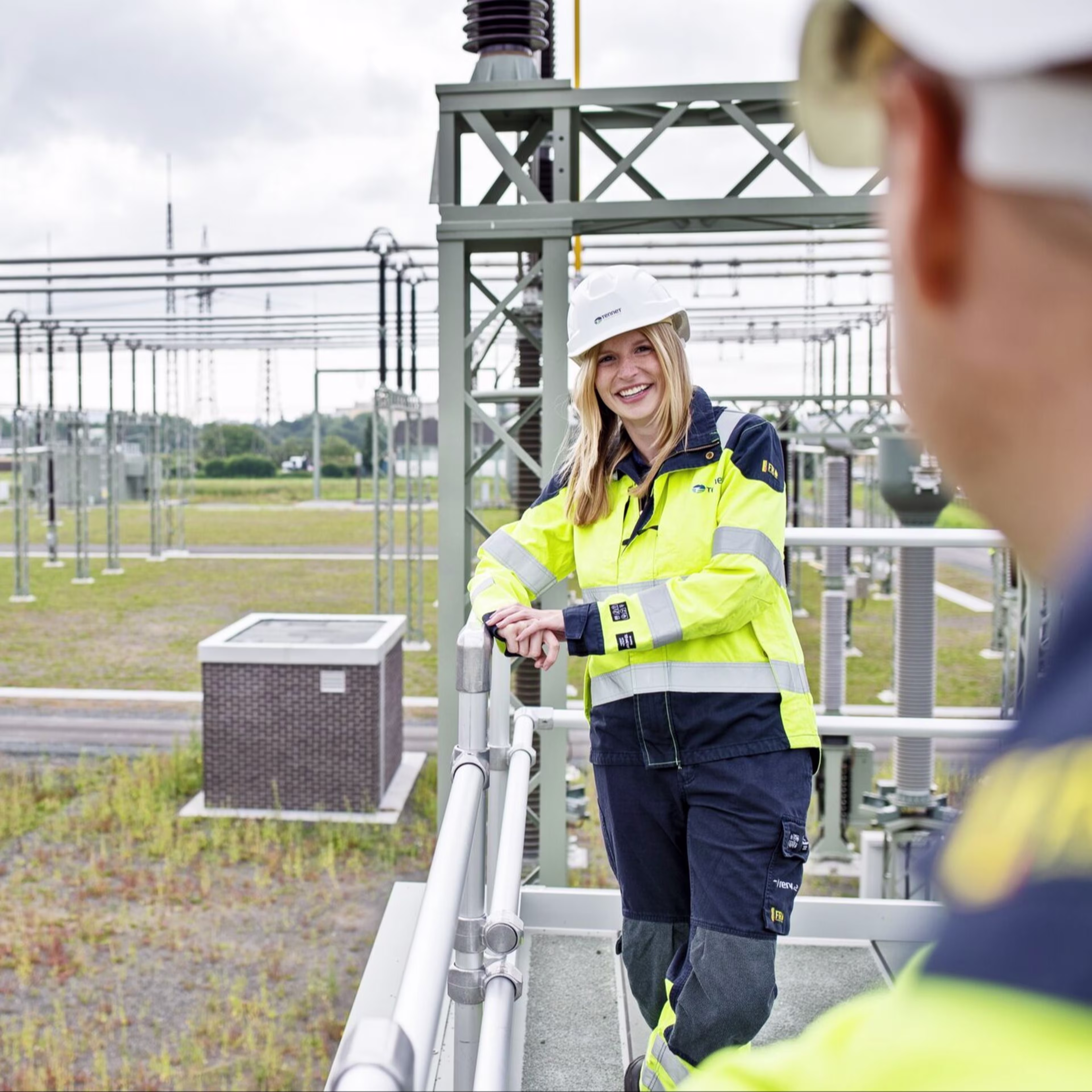 Frau mit Helm und Sicherheitskleidung bei Umspannwerk