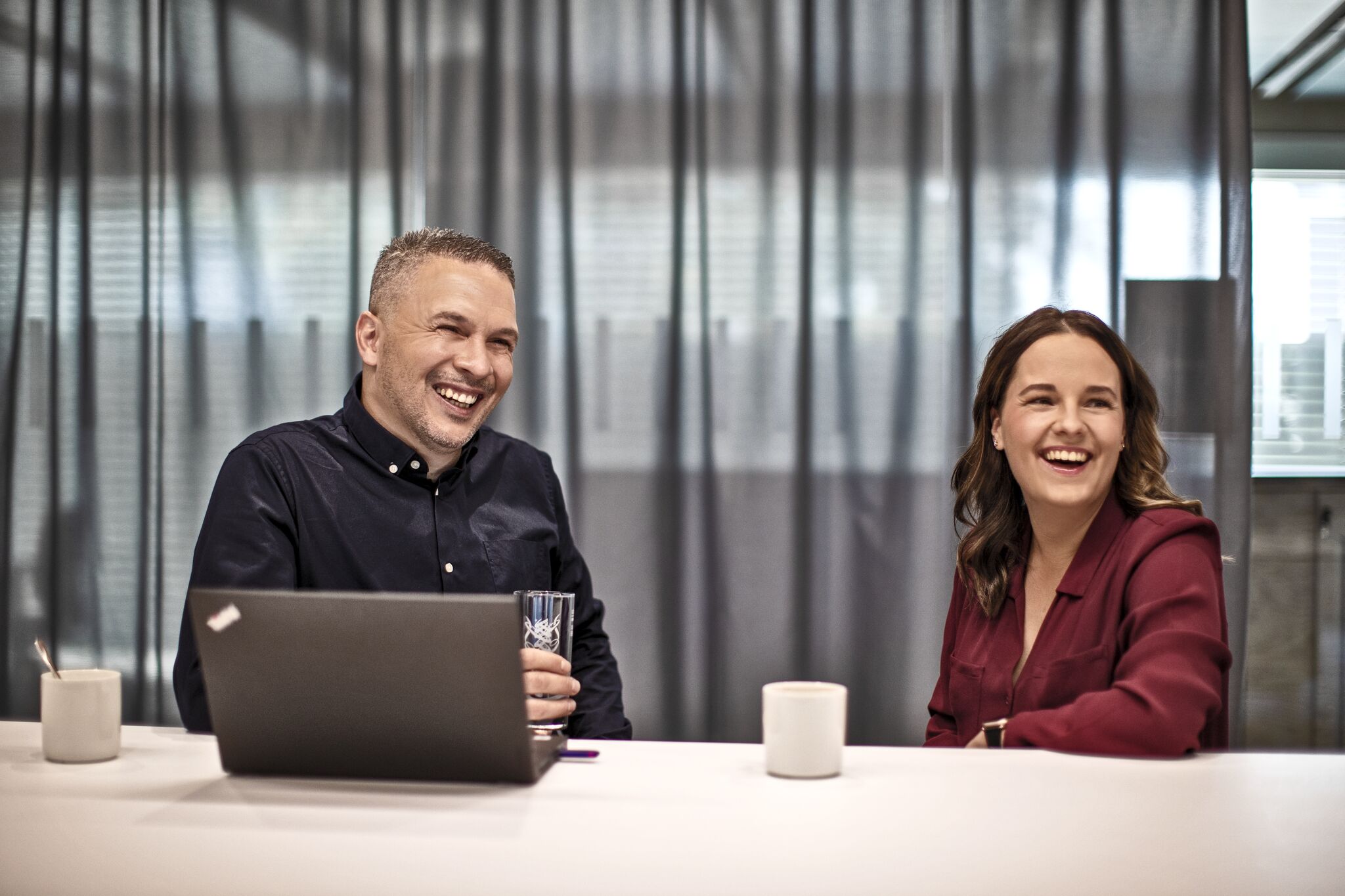 Lachender Mann und lachende Frau in Besprechungssituation